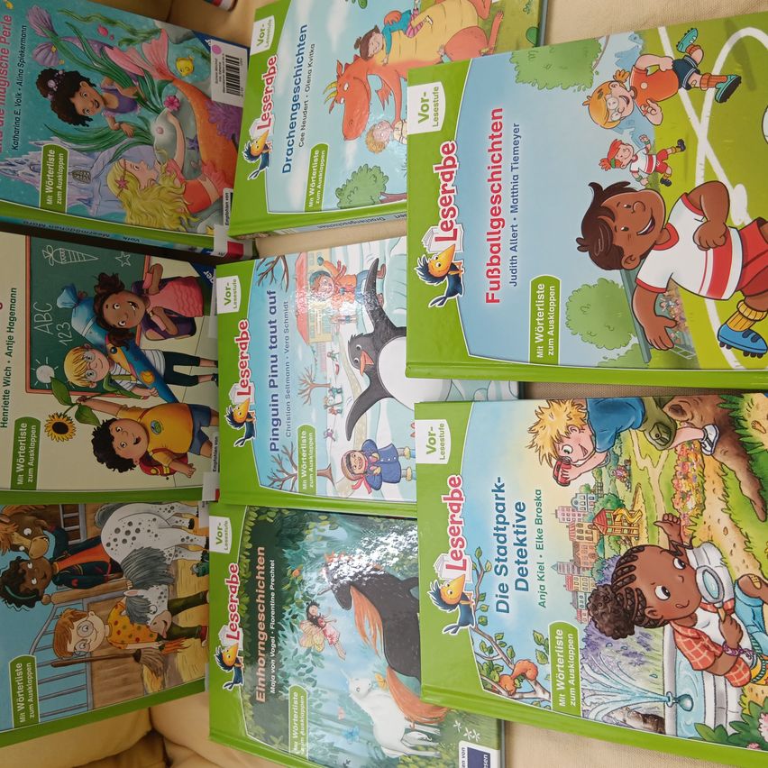 Eine Sammlung grüner Bücher mit den Titeln 'Leserabe' und 'Pinguim taust auf' ist auf einer Oberfläche gestapelt. Sie haben farbenfrohe Illustrationen von Kindern und Tieren auf ihren Titelseiten.