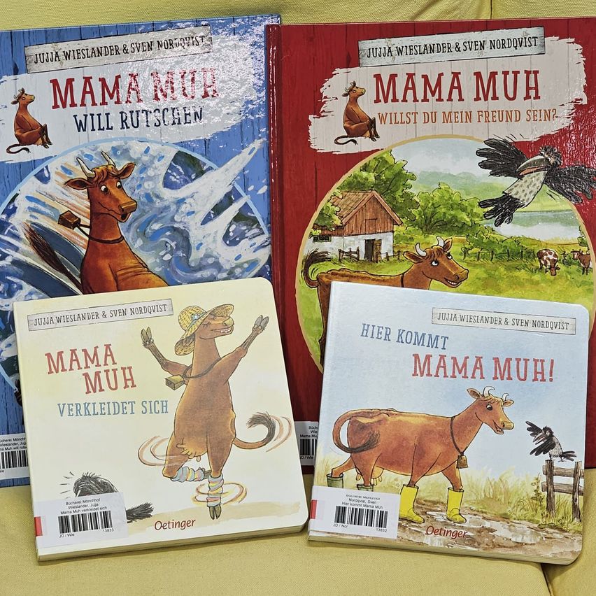 Four books are shown. The first two are blue and red with a cow and a bird. The last two are white with a cow and a bird. All books say Mama Muh.