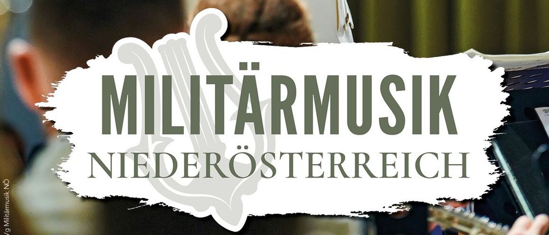 Ein älterer Mann in einer weißen Militäruniform mit goldenen Verzierungen und einem Dirigentenstab dirigiert. Darunter steht der Text 'MILITÄRMUSIK'. Mehrere Personen sitzen im Vordergrund.