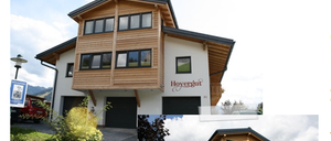 Ein Werbeplakat für Hoyergut, ein familiengeführtes Ferienhaus mit Balkon und Blumen. Adresse und Kontaktinformationen sind enthalten.