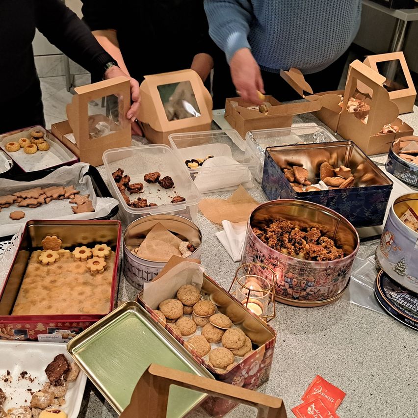 Ein Tisch voller verschiedener Kekse und Gebäck in Schachteln und Dosen. Verschiedene Kekssorten sind in Behältern und Schachteln angeordnet.