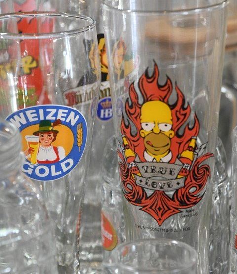Nahaufnahme mehrerer Trinkgläser mit verschiedenen Designs, einschließlich eines Homer Simpson Designs mit Flammen und den Worten True Love.