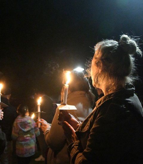 Eine Gruppe von Menschen hält brennende Kerzen in der dunklen Nacht, vielleicht bei einer Zeremonie.