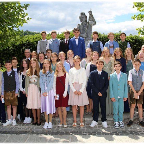 Eine Gruppe von Schülern und Lehrern posiert für ein Foto vor einer Statue an einem sonnigen Tag.