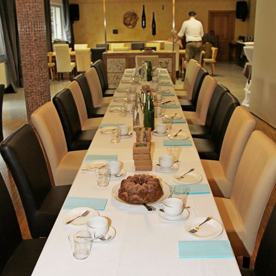 Ein langer Tisch für eine Mahlzeit mit Stühlen auf beiden Seiten, einem Kuchen in der Mitte und einem Mann im Hintergrund.