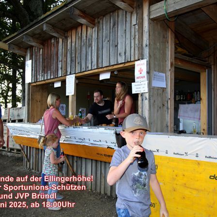 Ein junger Junge trinkt an einem Außenstand eine Limonade, während eine Familie und Arbeiter in der Nähe sind. Es gibt Schilder an der Wand und eine Bekanntmachung über eine Sportunionsveranstaltung.