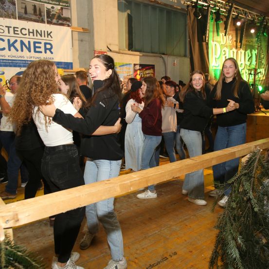 Eine Gruppe junger Frauen tanzt auf einer Party, einige lächeln, während andere in einem großen Raum zusehen.