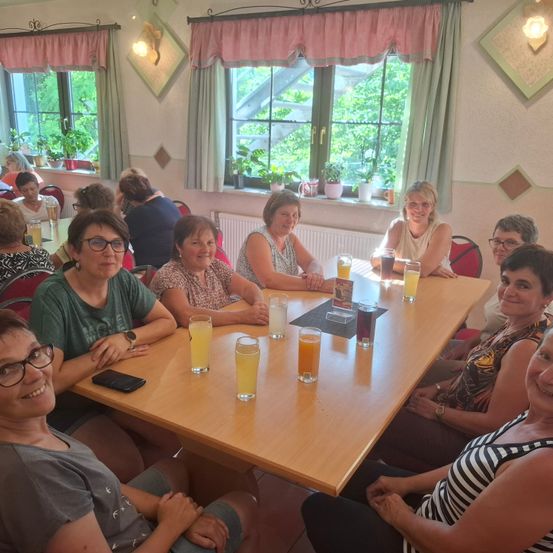 Eine Gruppe von Frauen sitzt mit Getränken um einen Tisch herum, lächelt und posiert für ein Foto in einem Restaurant.