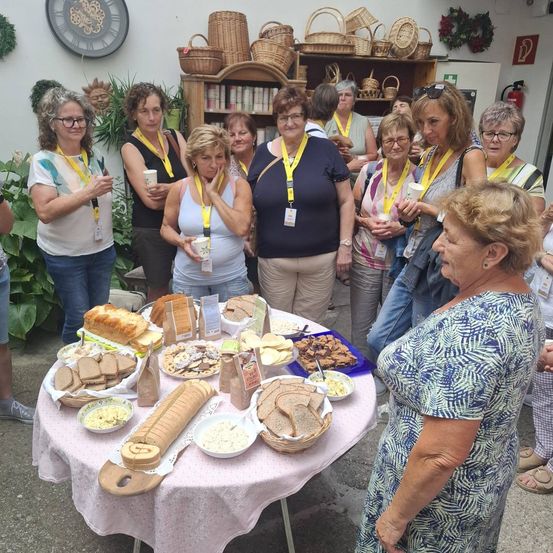 Eine Gruppe von Frauen mit Namensschildern um den Hals versammelt sich um einen Tisch mit verschiedenen Speisen.