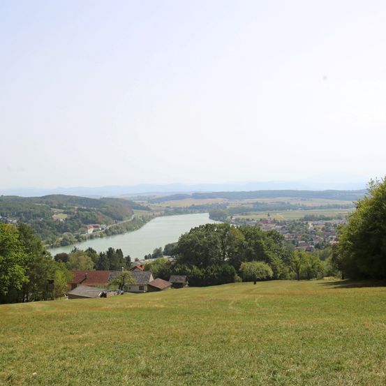 Luftaufnahme einer friedlichen Landschaft mit einem Fluss, Häusern und üppigem Grün unter klarem Himmel.