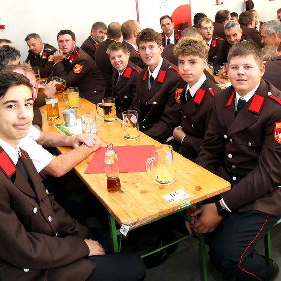 Eine Gruppe junger Männer in Uniform sitzt an einem Tisch mit Getränken, wahrscheinlich bei einer formellen Veranstaltung.