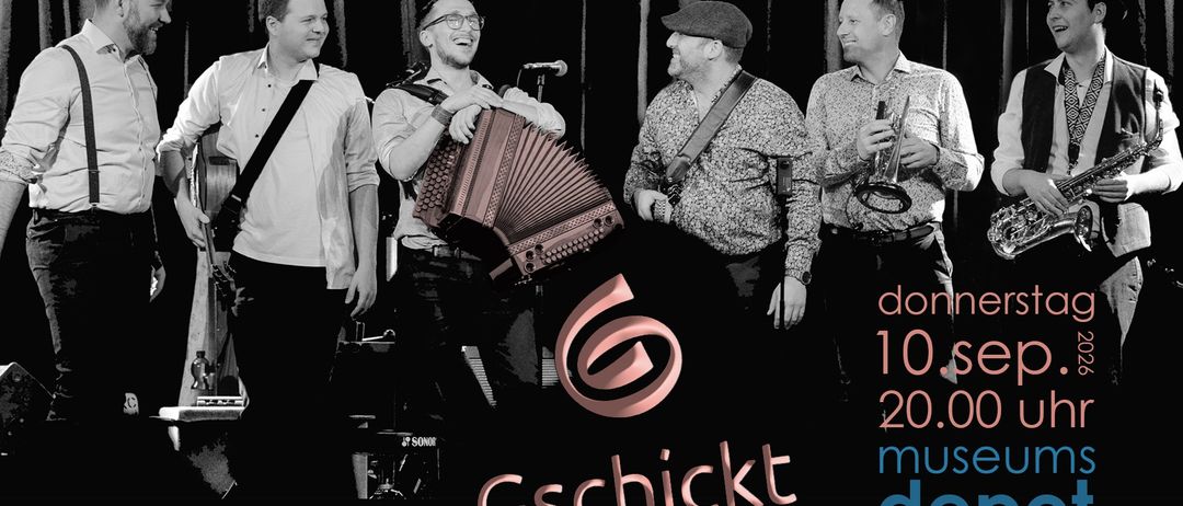 Vier Männer in einer Band, einer hält ein Akkordeon, ein anderer eine Trompete, stehen vor einem Mikrofon mit einem Logo in der Mitte.