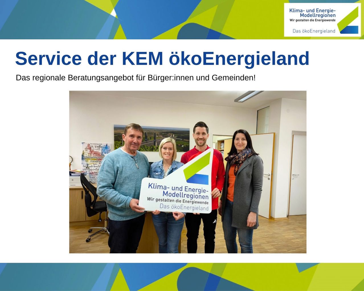 Gruppenfoto von vier Personen, die in einem Büro stehen und ein Schild mit der Aufschrift Klima- und Energie-Modellregionen halten. Der Text oben lautet Service der KEM ökoEnergieland.