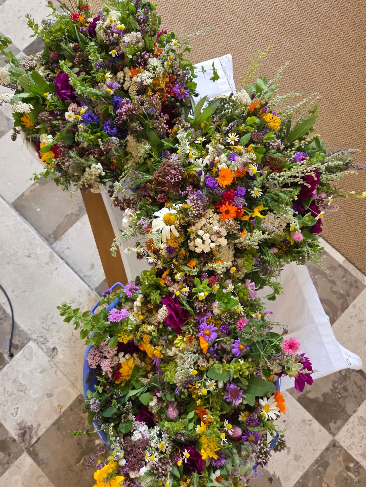 Eine farbenfrohe Blumenarrangement mit einer Mischung aus Wildblumen und Gartenblumen, in einer kreisförmigen Form auf einem gefliesten Boden angeordnet.