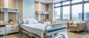 Ein sauberes Krankenhauszimmer mit einem Bett, einem Stuhl und Fenstern mit Blick auf die Stadt.