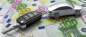 Ein Autoschlüssel liegt auf einem Stapel Euro-Banknoten. Der Schlüssel ist mit einem Spielzeugauto verbunden.