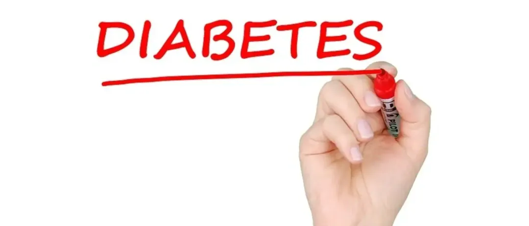 Eine Hand hält einen roten Marker und schreibt das Wort Diabetes auf einen weißen Hintergrund.