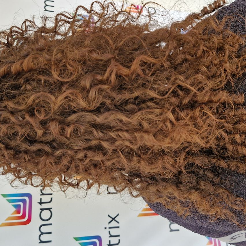 Ein Nahaufnahme von braunem, lockigem Haar, das vor einem weißen Hintergrund mit Logos präsentiert wird. Das Haar sieht feucht aus und ist voluminös gestylt.