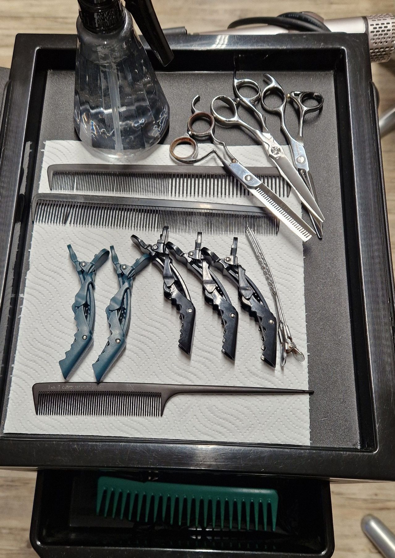 Ein Tablett zeigt Scheren, Kämme und Clips. Drei Scheren sind geöffnet. Die Kämme haben verschiedene Zinken. Die Clips sind blau und schwarz.