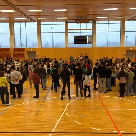 Bild enthält, People, Person, Floor, Flooring, Wood, Building, Hardwood, Crowd, Indoors, Classroom