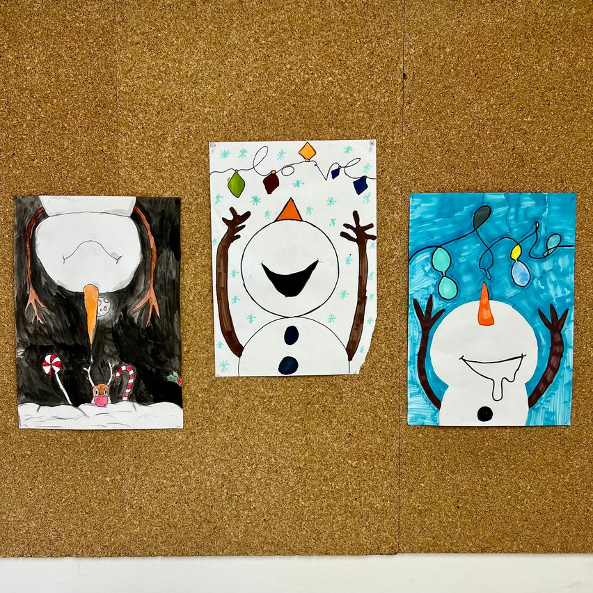 Drei Gemälde sind an einer Korktafel aufgehängt. Das linke Gemälde zeigt einen Pinguin, das mittlere einen lächelnden Schneemann und das rechte einen schmelzenden Schneemann.