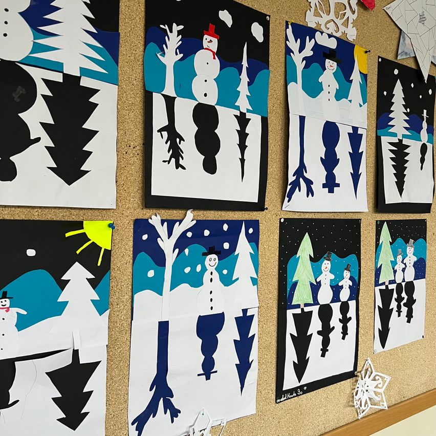 Ein Anschlagbrett zeigt mehrere winterliche Kunstwerke, darunter Schneemänner, Bäume und Schneeflocken. Jedes Kunstwerk hat ein einzigartiges Design und Farbschema und schafft eine festliche und künstlerische Präsentation.