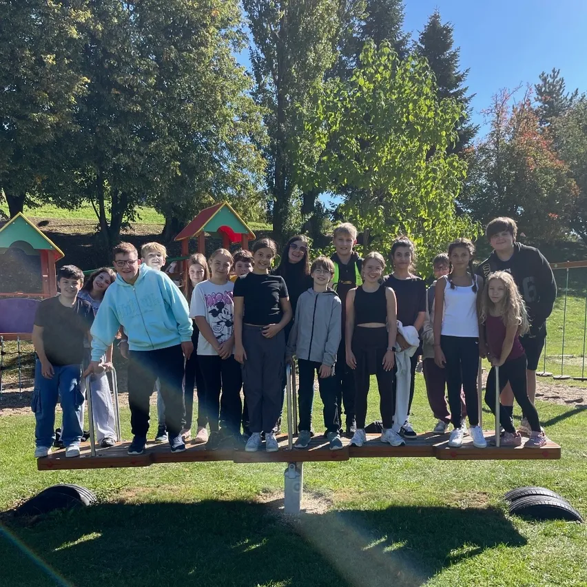 Eine Gruppe von Kindern und Erwachsenen posiert für ein Foto auf einem Wippgerät in einem Park.