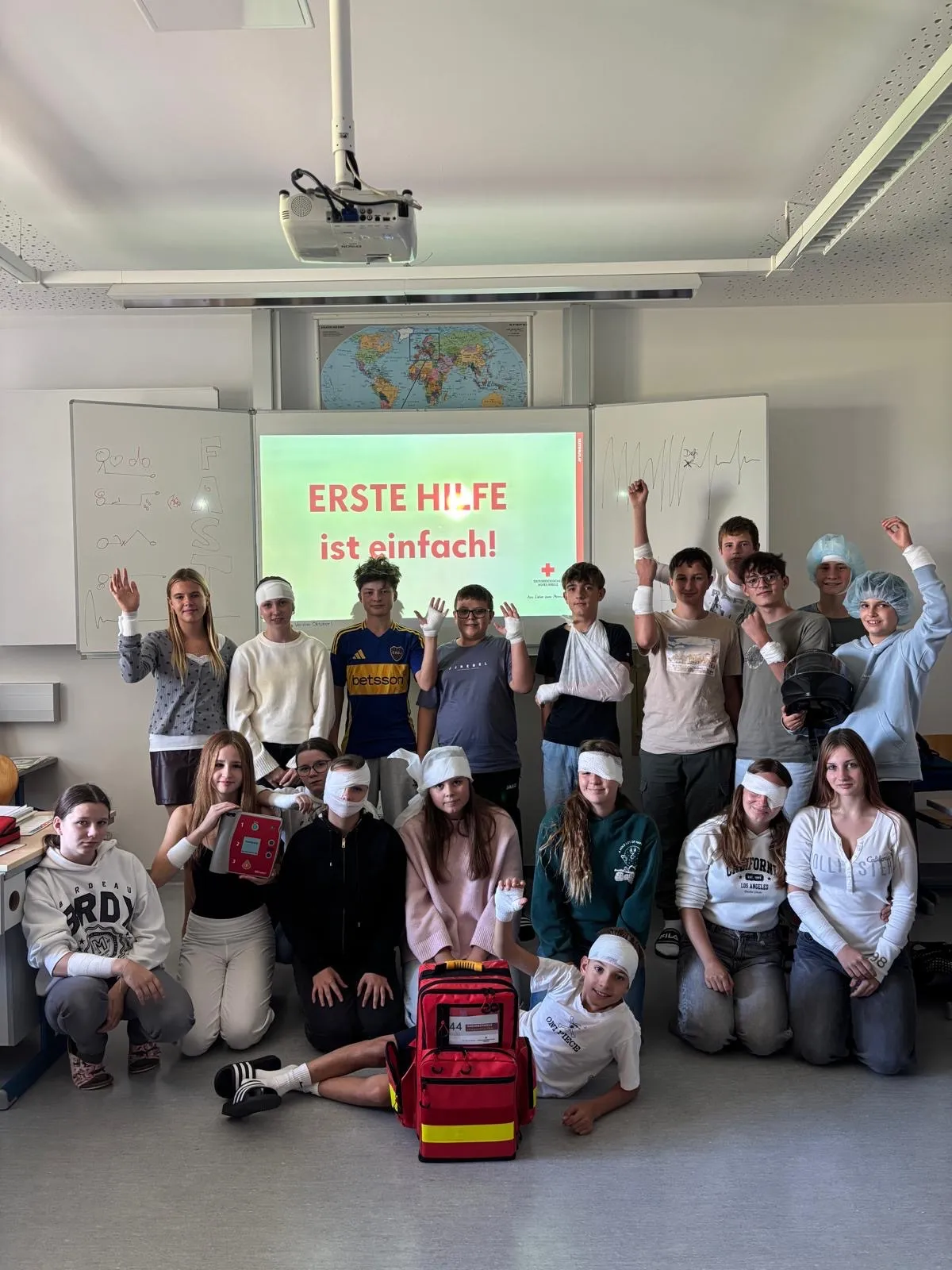 Eine Gruppe von Menschen, die in Verbänden und medizinischer Ausrüstung gekleidet sind, posiert für ein Foto im Klassenzimmer.