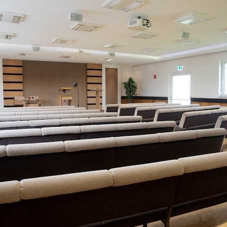 Bild enthält, People, Indoors, Crowd, Classroom, School, Audience, Lecture, Hall, Lecture Hall, Couch