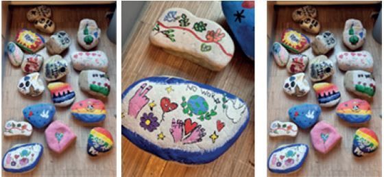 Drei Bilder zeigen bemalte Steine auf einer Holzoberfläche. Die erste und dritte Bilder zeigen mehrere Steine mit verschiedenen Designs. Das zweite Bild zeigt einen größeren Stein mit den Worten 'KEINE ARBEIT' und anderen bunten Zeichnungen.