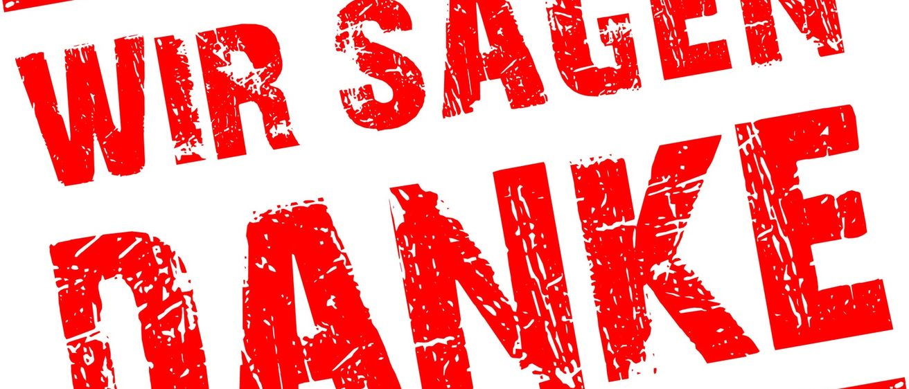 Ein roter Stempel mit weißem Rand sagt Wir sagen Danke, was im Englischen Wir sagen Danke bedeutet. Die Buchstaben sind in einer verwitterten Schrift gedruckt.