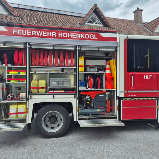 Die offenen Türen eines roten und weißen Feuerwehrfahrzeuges zeigen das Innere, vollgepackt mit verschiedenen Feuerwehrausrüstungen und Werkzeugen.