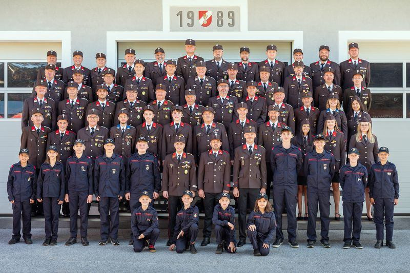 Eine Gruppe von Menschen in Uniform, möglicherweise Militärangehörige, posiert für ein Foto vor einem Gebäude mit der Nummer 1989.