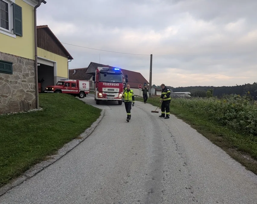 Ein Feuerwehrauto steht am Straßenrand, Feuerwehrleute sind beim Aufräumen. Ein anderes Feuerwehrauto verlässt die Garage.