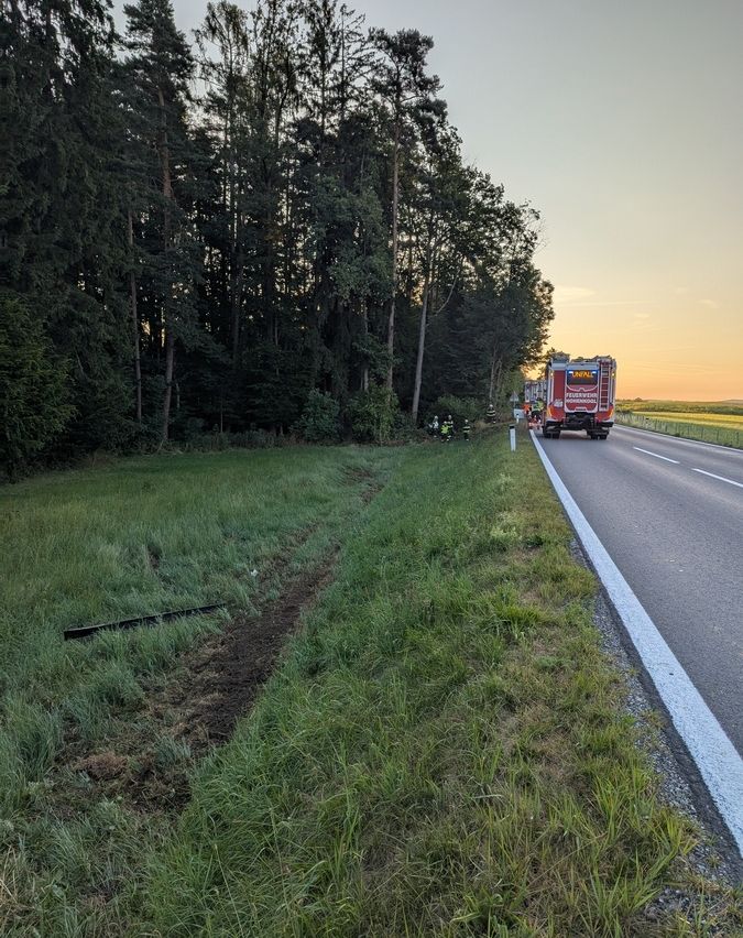 Ein Rettungsdienst reagiert auf einen Vorfall an einer Straße mit Bäumen auf der Seite. Das Fahrzeug ist am Straßenrand geparkt.