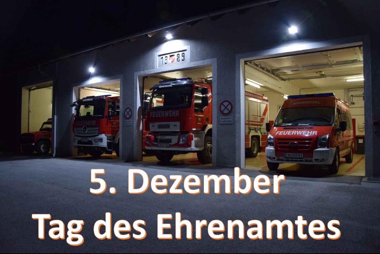 Ein Bild einer Feuerwehrwache mit drei Feuerwehrfahrzeugen, die in den Garagen geparkt sind. Der Text 5. Dezember und des Ehrenamtes wird im Vordergrund angezeigt.