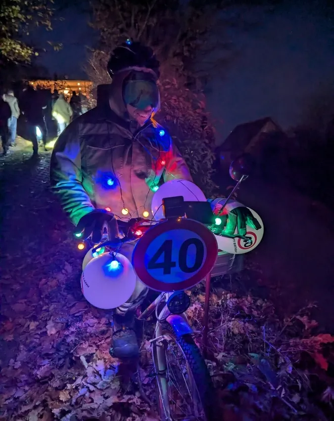 Eine Person mit einem Helm mit bunten Lichtern fährt ein Fahrrad, das mit bunten Lichtern und einem Schild mit einer Geschwindigkeitsbegrenzung von 40 verziert ist.