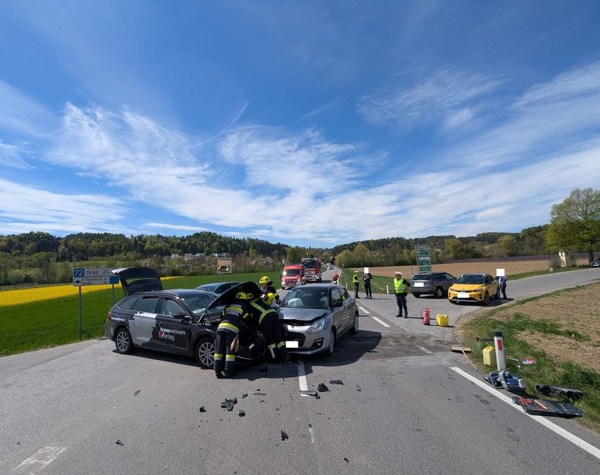 Rettungskräfte kümmern sich um zwei Autos, die auf einer Landstraße kollidiert sind, mit Zuschauern in der Nähe.