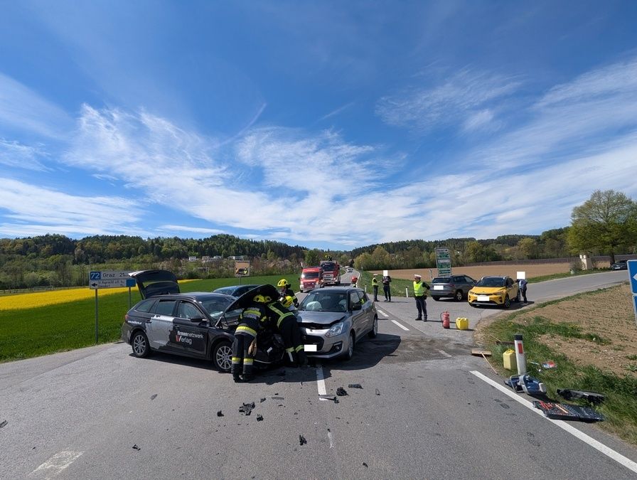 Rettungskräfte kümmern sich um zwei Autos, die auf einer Landstraße kollidiert sind, mit Zuschauern in der Nähe.