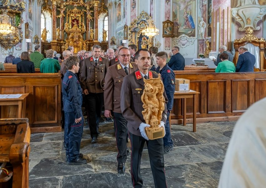 Eine Gruppe von Männern in Uniformen, die in einer Kirche mit einem hölzernen Altar und Dekorationen im Hintergrund gehen.