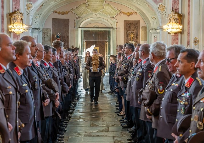 Eine formelle Zeremonie mit Offizieren in Uniform, die in Reihen stehen. Eine Person, die eine goldene Trophäe trägt, geht den Gang entlang.