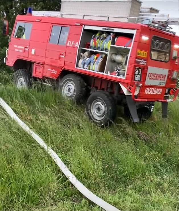Ein roter Feuerwehrwagen mit der Bezeichnung KLF-A und der Nummer 681 steht auf einem Grasfeld. Die hintere Tür ist geöffnet und zeigt verschiedene Ausrüstungsgegenstände im Inneren.