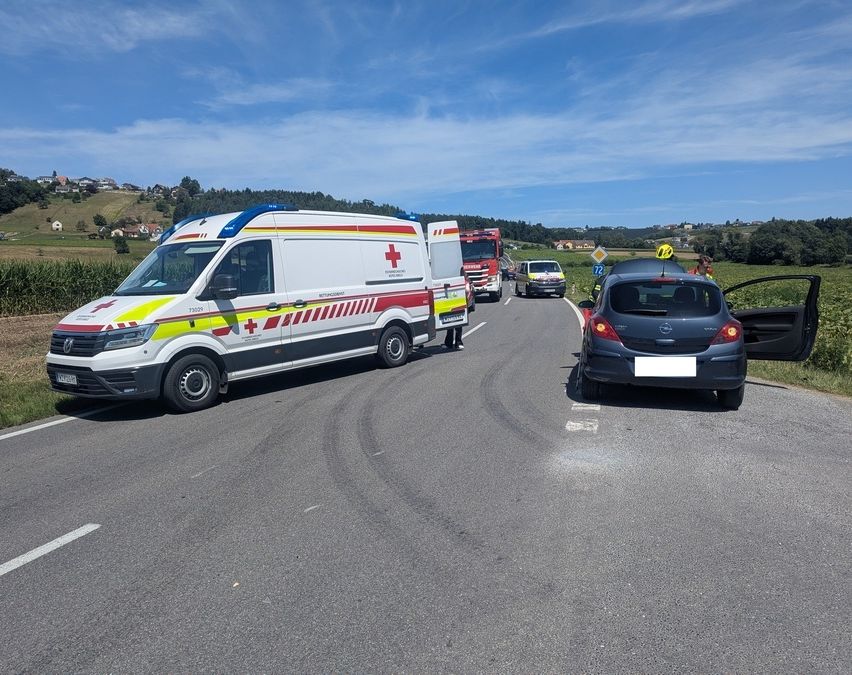 Ein Krankenwagen steht mit offener Tür am Straßenrand. Eine Person steht in der Nähe des Krankenwagens. Ein weiteres Fahrzeug ist dahinter geparkt.