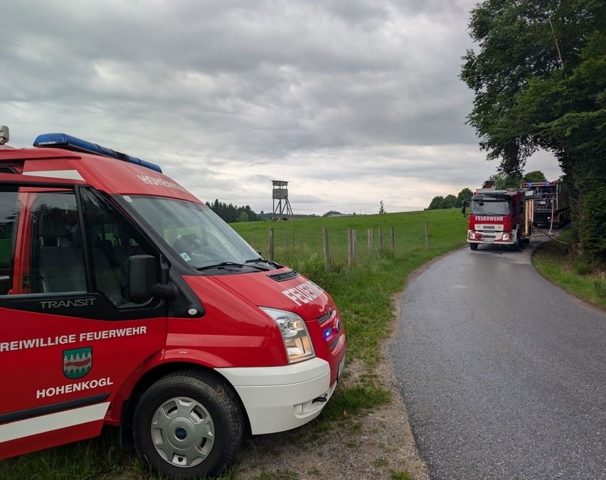 Ein Feuerwehrwagen von Hohenkogl steht am Straßenrand, während ein anderer Feuerwehrwagen im Hintergrund fährt.