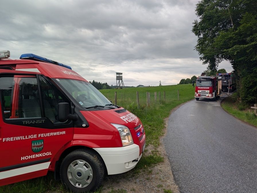 Ein Feuerwehrwagen von Hohenkogl steht am Straßenrand, während ein anderer Feuerwehrwagen im Hintergrund fährt.