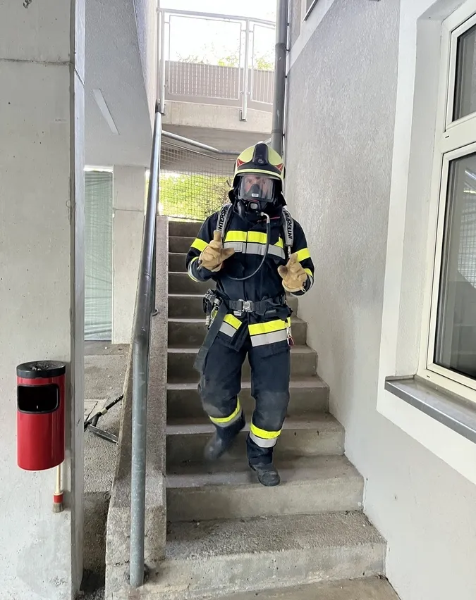 Ein Feuerwehrmann in voller Ausrüstung, einschließlich Helm, Maske und Schutzanzug, klettert eine Treppe hinauf.