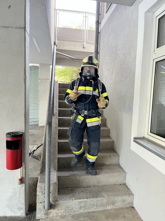 Ein Feuerwehrmann in voller Ausrüstung, einschließlich Helm, Maske und Schutzanzug, klettert eine Treppe hinauf.