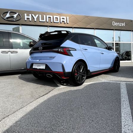Ein hellblauer Hyundai N-Wagen mit dem Kennzeichen 20N ist vor einem Hyundai-Händler geparkt.