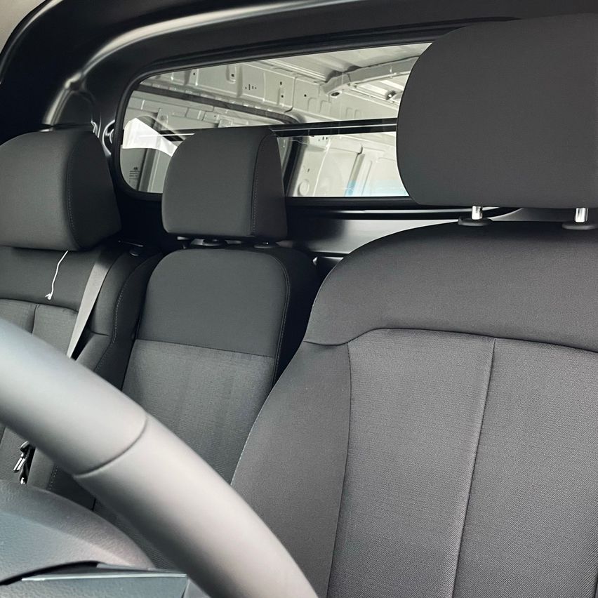 Innenraum eines Lieferwagens mit Fahrersitz und zwei Passagiersitzen, alle in grauem Leder.