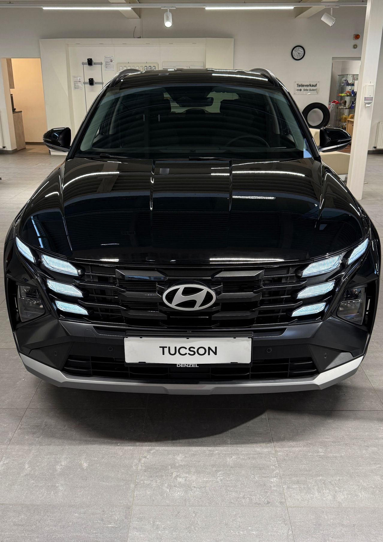 Ein schwarzer Hyundai Tucson SUV wird in einem Showroom mit einem weißen Nummernschild ausgestellt, das Tucson liest.